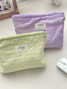 Set of two striped canvas storage bags in soft yellow and purple on a tidy desktop