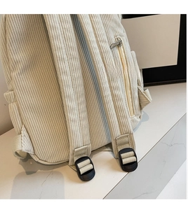 Detail of adjustable shoulder straps and side zipper pocket on corduroy backpack