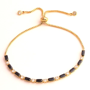 Detail of gold bracelet with black rectangle zircon and clear stones featuring slider clasp