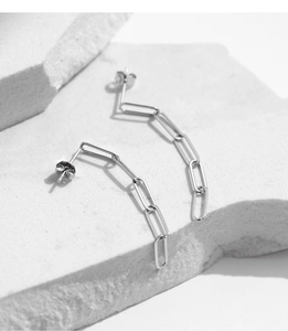 Close-up of S925 sterling silver paperclip chain earrings on white stone surface