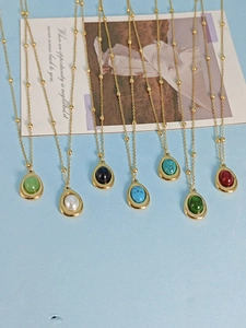 Artistic display of multiple gold-beaded necklaces with colorful gemstone pendants