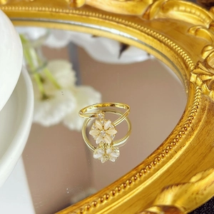 Macro detail of rotating gold flower ring with white petals on vintage mirror