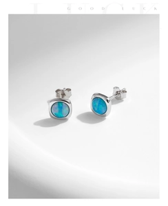 Detail of S925 sterling silver square stud earrings with blue opal on a white pedestal