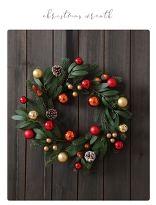 Detail of Christmas wreath with red and gold ornaments and pine cones on dark wood