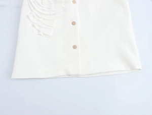 Detailed close-up of white blazer hem featuring layered floral trim and golden buttons