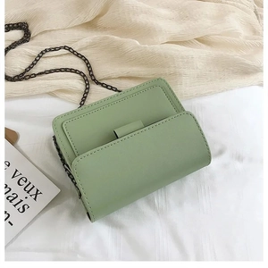 Macro shot of light green PU leather flap bag featuring grey metal chain shoulder strap