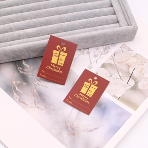 Macro shot of red Christmas gift tags with gold silk print patterns on velvet tray