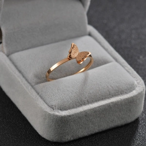 Macro shot of rose gold butterfly ring with frosted wings on gray velvet box