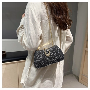 Detail of black evening bag with white abstract patterns and a golden horseshoe diamond clasp