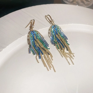 Macro shot of colorful gradient tassel earrings with rhinestones on a white background