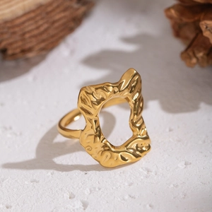 Irregular gold hollow ring with hammered texture displayed on a natural stone surface