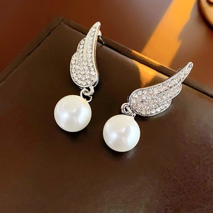 Close-up of silver wings earrings with clear crystals and a hanging white round faux pearl