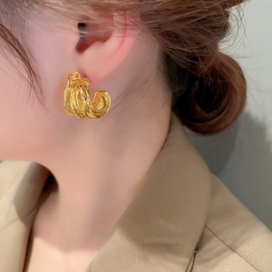 Close-up of a model wearing golden multi-layered C-shaped metal hoop earrings for women