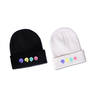 Berretti in maglia bianchi e neri con icone smiley colorate e fuse sul risvolto