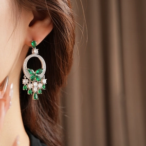 Gros plan de boucles d'oreilles de luxe en argent avec gouttes d'émeraude et franges zircon