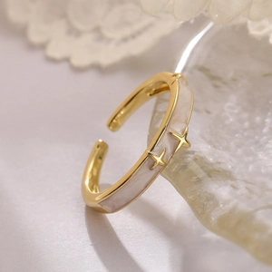 Macro shot of gold adjustable ring with beige enamel and embossed stars on glass