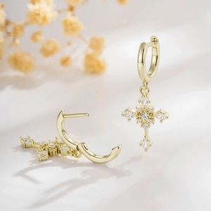Elegant gold hoop earrings with sparkling crystal cross charms displayed on a soft background