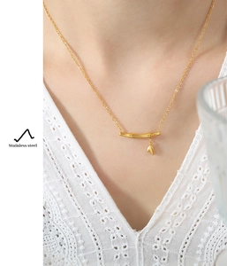 Détail d'un collier en acier inoxydable doré avec pendentif en bambou et feuille