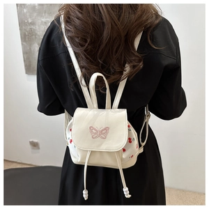 Close-up of white PU leather mini backpack with cherry print and pink butterfly embroidery