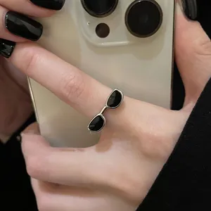 Détail de la bague argentée Y2K avec un design créatif de lunettes de soleil noires
