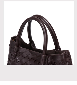 Close-up of dark brown hand-woven leather bucket bag with gold hardware detail