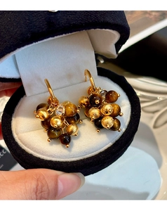 Detail of tiger eye beads and brushed gold metal spheres on luxury cluster earrings