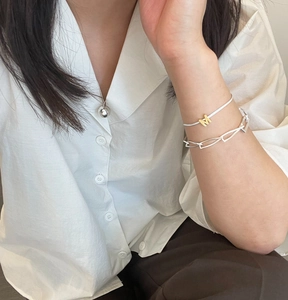 Detail of 925 sterling silver ball necklace and gold letter charm bracelet on model