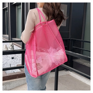 Detailed side view of a large pink mesh tote bag with breathable polyester texture