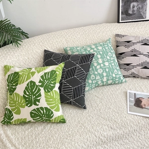 Green leaf and geometric cotton linen cushion covers set displayed on white rug