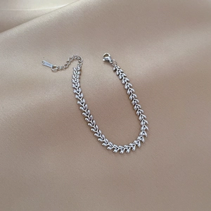 Close-up of silver wheat chain bracelet with lobster clasp and S.STEEL engraved tag