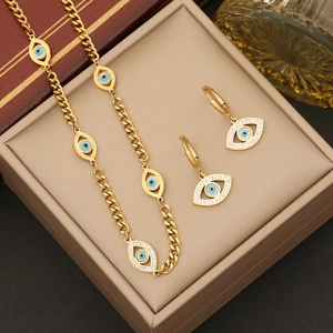 Gold evil eye jewelry set with blue center and crystals on a thick Cuban chain