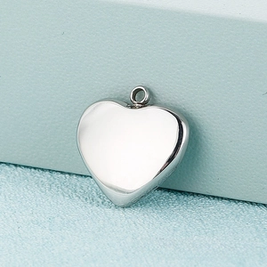 Close-up of polished silver heart charm with mirror finish on blue minimalist base