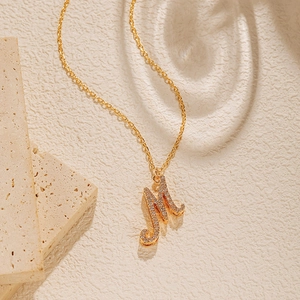 Macro detail of 18K gold plated chain and M pendant set with sparkling zircons