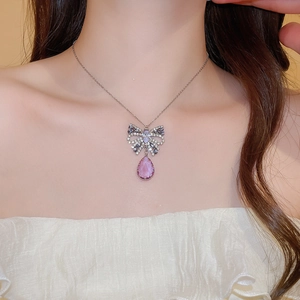 Close-up of silver chain with sparkling butterfly and pink teardrop gemstone necklace
