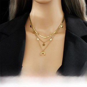 Detailed view of triple-layered gold necklaces with star and moon pendants on a black suit