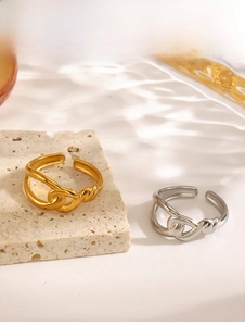 Detail of interlocking knot gold and silver plated crossover rings on textured background