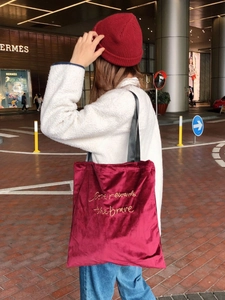 Retro burgundy velvet tote bag with chic gold letter embroidery shown in street style