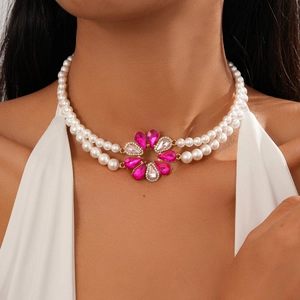 Close-up of double-layer pearl necklace featuring a pink crystal flower pendant on a model