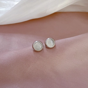 Macro shot of silver titanium steel earrings featuring round white cat eye stones