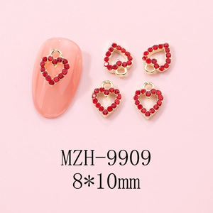 Close-up of gold-plated heart nail charms with red rhinestones in 8x10mm size