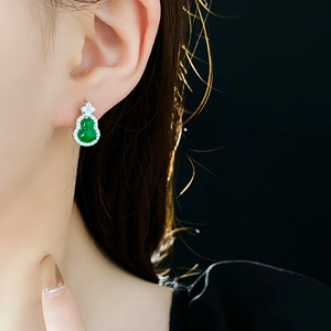 Close-up of model wearing green gourd earring with silver setting and zircon stones