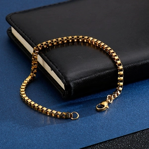 Sleek gold-plated stainless steel box chain bracelet with lobster clasp on notebook