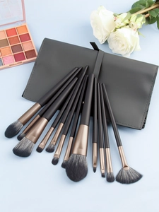 Detailed view of 13 professional makeup brushes displayed on a grey leather travel pouch