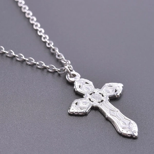Close-up of a silver stainless steel cross pendant necklace with detailed engravings