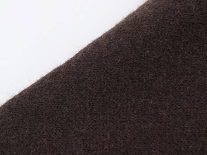 Dettaglio macro di morbido tessuto a maglia marrone scuro con trama spazzolata e fibre