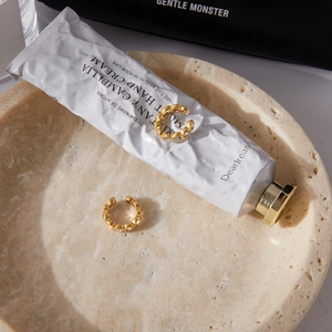 Detail view of 18K gold stainless steel ear cuffs with white zircon on a stone tray