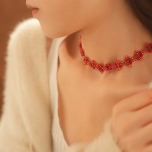 Close-up of a handmade red beaded choker necklace worn by a model in soft lighting