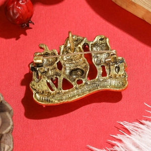 Back view of cute cartoon cat brooch in vintage gold finish with secure pin on red background