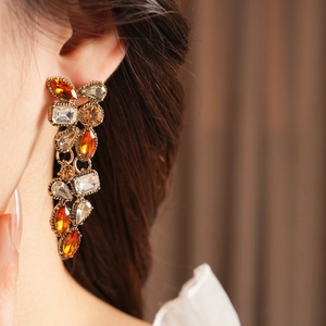 Close-up of vintage gold earrings with amber crystals worn by a model in warm lighting