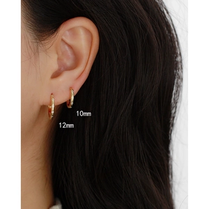 Detail shot showing the 10mm and 12mm gold paved diamond hoop earrings on a model